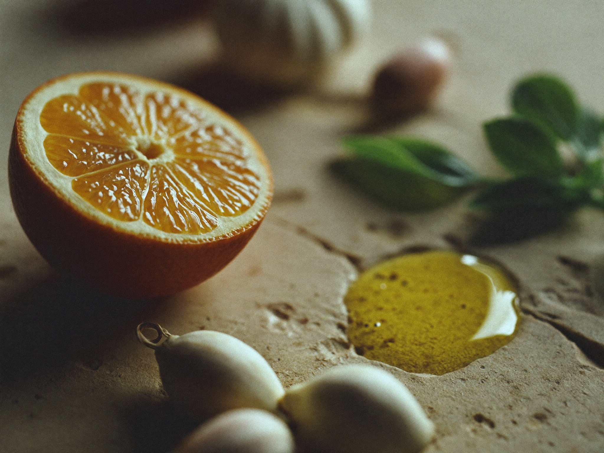 Close-up af friske råvarer — hele urter, en halveret citrus og olivenolie på en råstensoverflade